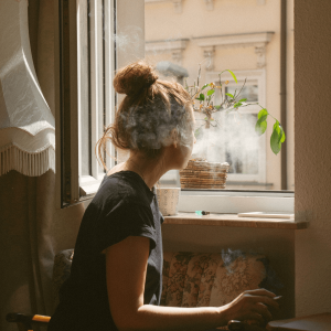 A woman smoking a joint and looking out the window