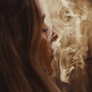 A woman with blonde hair blowing smoke