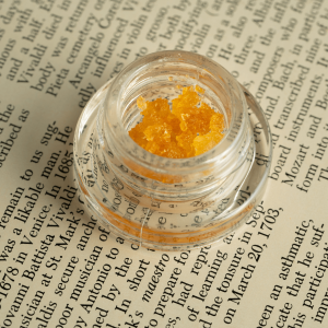 a small jar of gold cannabis concentrate
