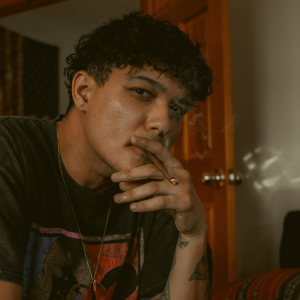a man with black curly hair smoking a blunt