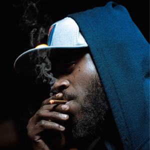 a man with a hat on smoking a blunt