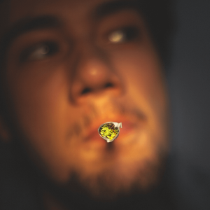 A man puffing a joint directly in front of the camera