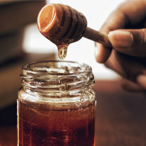 a person spooning honey from a jar