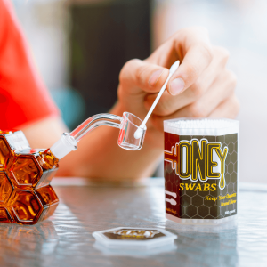 A person cleaning their dab rig with a cotton swab