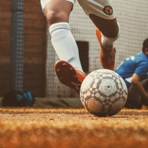 Person in orange cleats kicking a white soccer ball