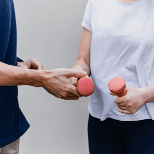 a man and woman holding pink dumbbells 