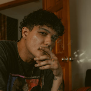 A man with curly hair smoking a blunt