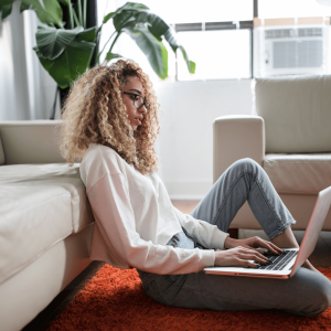 A woman sitting on the floor and using her computer