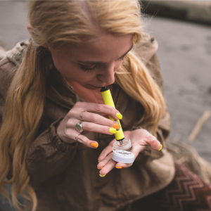 A woman holding a cannabis concentrate and taking a dab