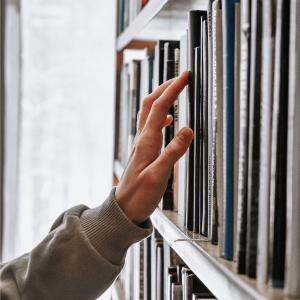 a person in a white long sleeve searching through books