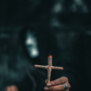 a man in a mask holding up a burning cross joint