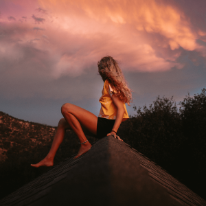 A woman sitting on a roof overlooking California mountains