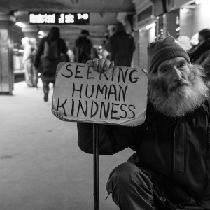A man holding a sign that says ‘seeking human kindness’