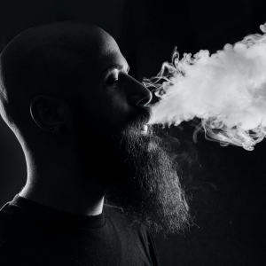 black and white photo of a man with a beard vaping