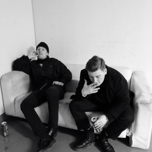 two men sitting on a couch and cross faded
