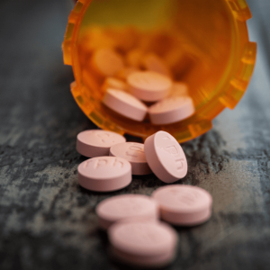 pink prescription pills spilling out of an orange bottle