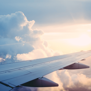 a plane wing flying through a blue sky with clouds 