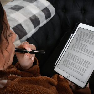 a woman reading a book and smoking a vape cartridge