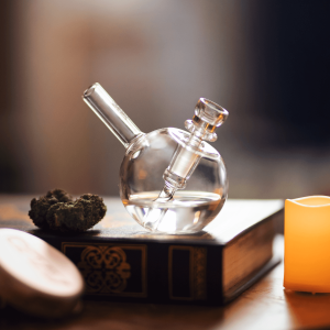 a clear glass bong pictured next to cannabis flower