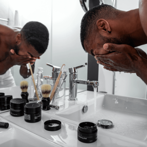 a man standing in front of a mirror and washing his face