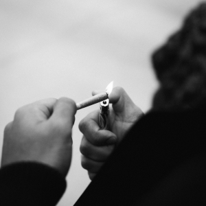 a black and white image of a person lighting a joint