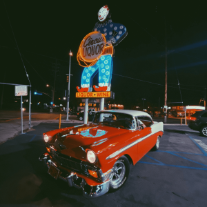 a red vintage car in front of a clown sign
