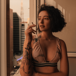 a woman smoking a joint and looking out the window