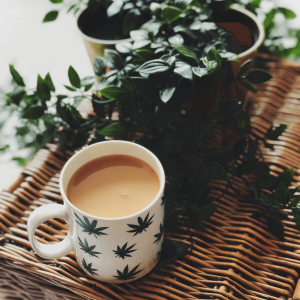 a coffee mug with coffee and weed leaves pictured