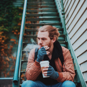 a man smoking and drinking from a coffee cup on steps