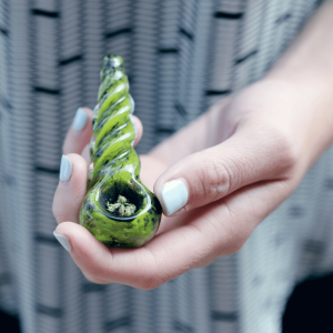 a person holding a green marijuana pipe