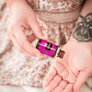 a woman in a floral dress dropping lavender essential oil in her palm
