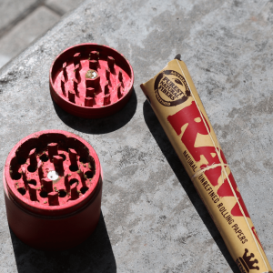 a red metal grinder next to a raw rolling cone