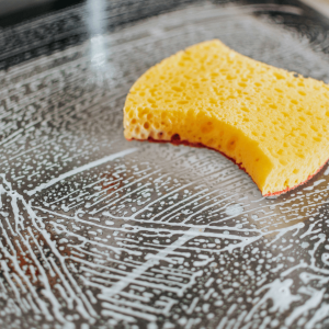a yellow sponge and soap suds on a clear glass countertop 