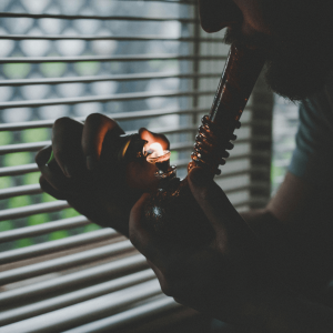 a man lighting a bong and taking a hit