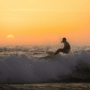 man surfing at sunset in carlsbad california
