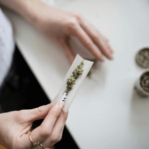a person holding a rolling paper with ground flower in it 