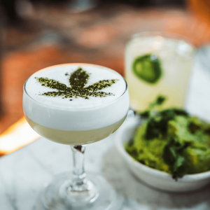 green cocktail with cannabis leaf garnish