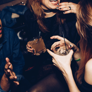 two women talking and drinking in a club