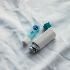 an inhaler next to a lip balm on top of a white sheet