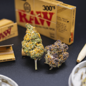 colorful cannabis buds pictured next to a grinder and rolling papers
