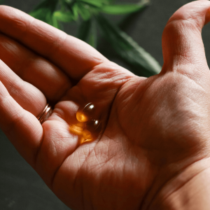 a person holding gold CBD capsules