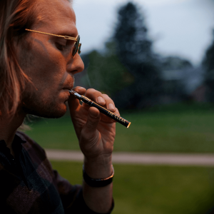 a man with long blonde hair smoking a vape pen