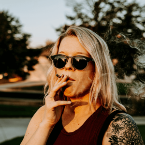 a blonde girl with a tattoo smoking a joint