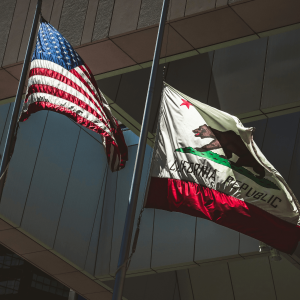 california and american flags waving in front of an office building