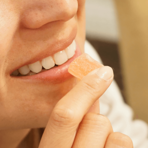 woman smiling and holding orange and white candy up to her mouth