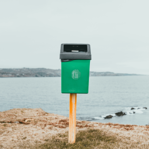 recycling bin on a post in front of the ocean