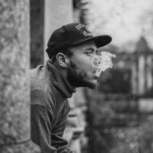 black and white image of a man smoking on a balcony