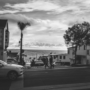 black and white image of cars driving near the beach