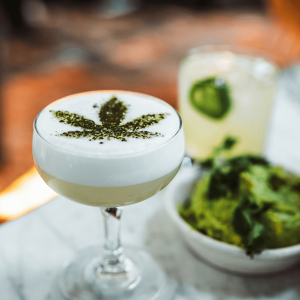 a green cocktail with a cannabis leaf on top