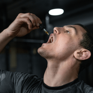 a man consuming gold liquid from a dropper